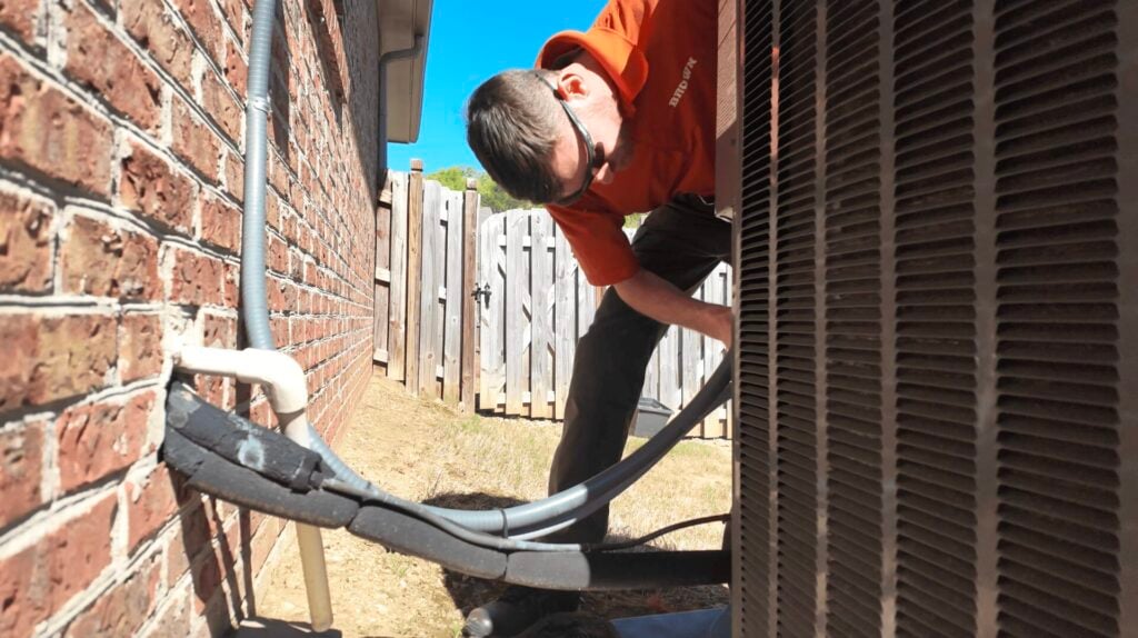 Brown Heating and Cooling technician servicing an outdoor air conditioner for Trane HVAC repair in Birmingham Alabama